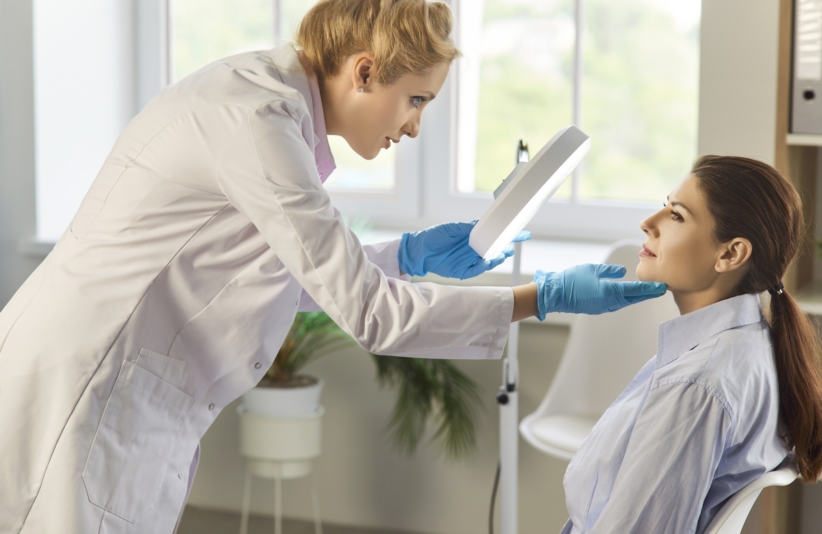 Provider examining patient's skin to assess if she is a good candidate for microneedling