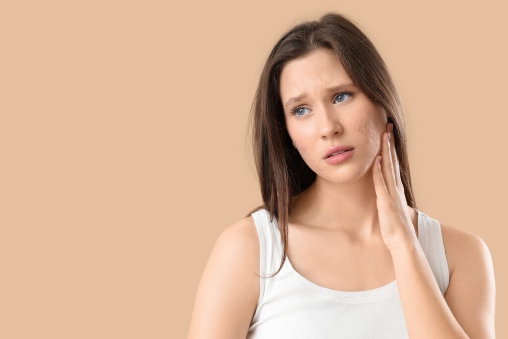Woman touching her cheek concerned about skin texture after acne
