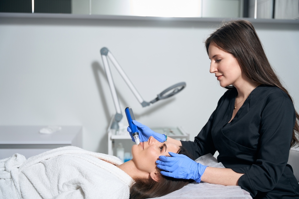 Provider performing microneedling to stimulate collagen production on patient's forehead
